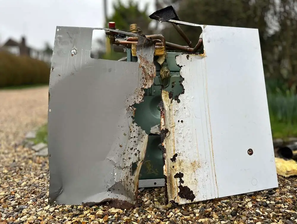 The old Grant oil boiler removed from the property, showing extensive corrosion to the casing.